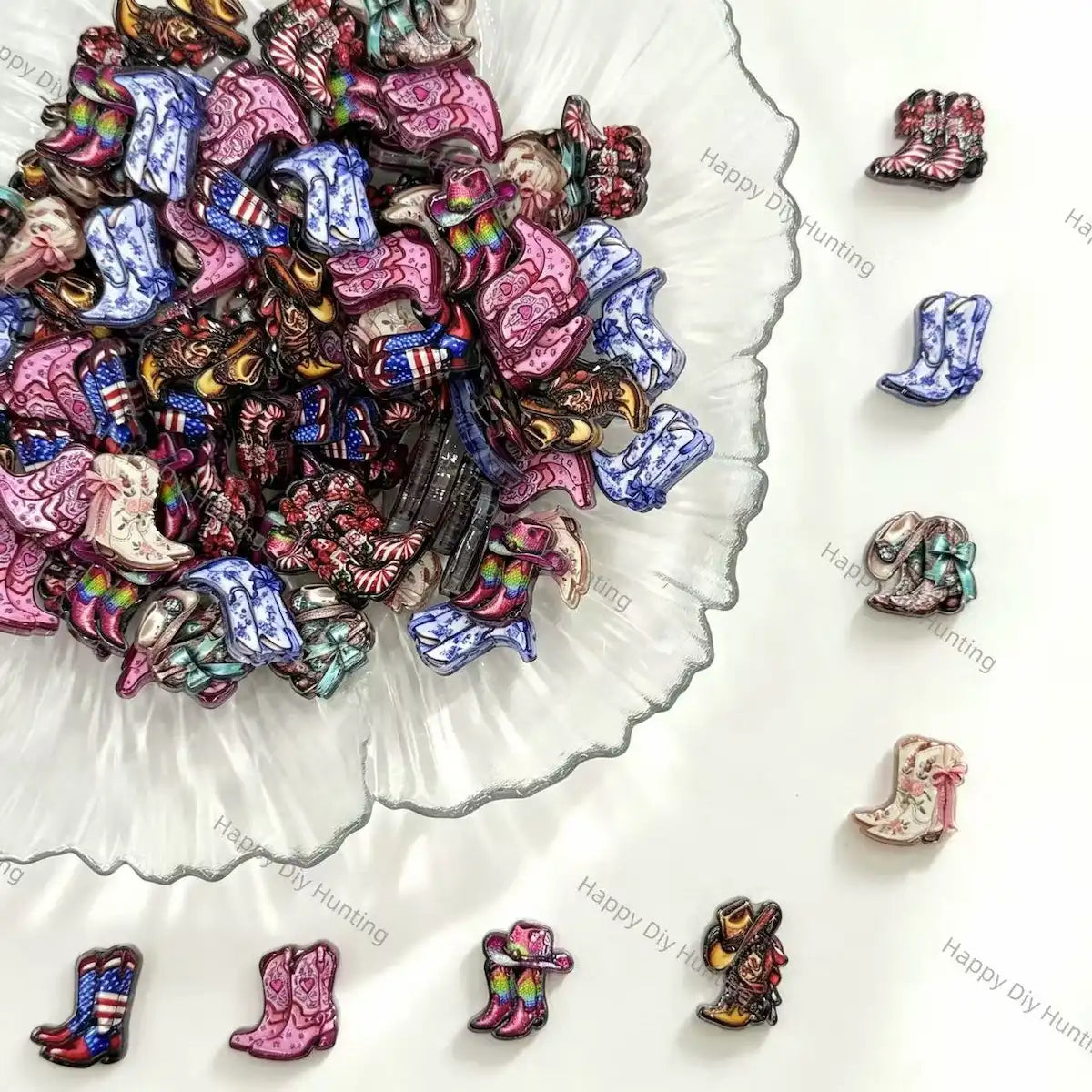 A pile of small cowboy boot charms or beads in assorted colors and patterns, arranged on a white surface with a scalloped glass dish and several individual boots displayed around it.