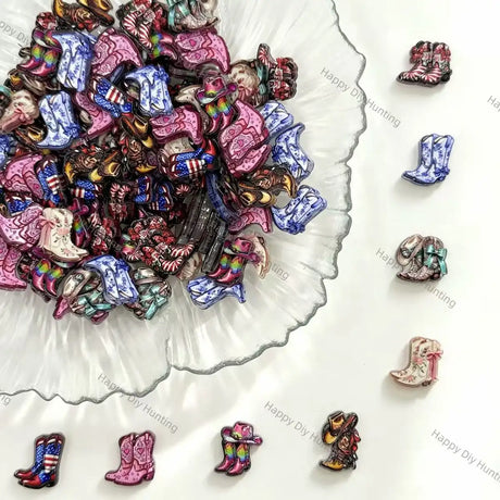 A pile of small cowboy boot charms or beads in assorted colors and patterns, arranged on a white surface with a scalloped glass dish and several individual boots displayed around it.