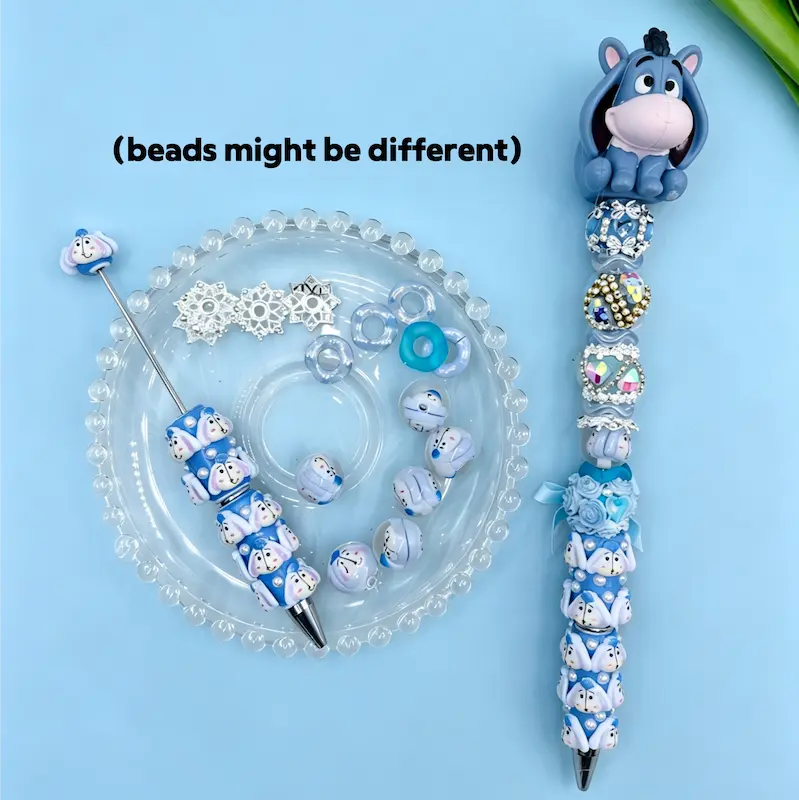 Eeyore inspired light blue beadable pen kit showcasing a blue donkey pen topper, custom floral silicone beads, and elegant rhinestone accessories.