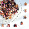 A pile of small rectangular acrylic charms or pins featuring illustrated blonde and dark-haired women, arranged on a clear scalloped dish with several individual pieces placed around it on a white background.