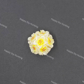 A small white and yellow flower-shaped bead or charm with orange-red speckles, centered on a dark gray background with repeated 'Happy DIY Hunting' watermark text.
