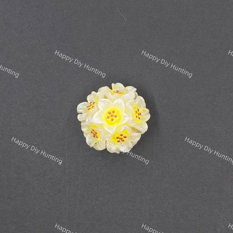 A small white and yellow flower-shaped bead or charm with orange-red speckles, centered on a dark gray background with repeated 'Happy DIY Hunting' watermark text.
