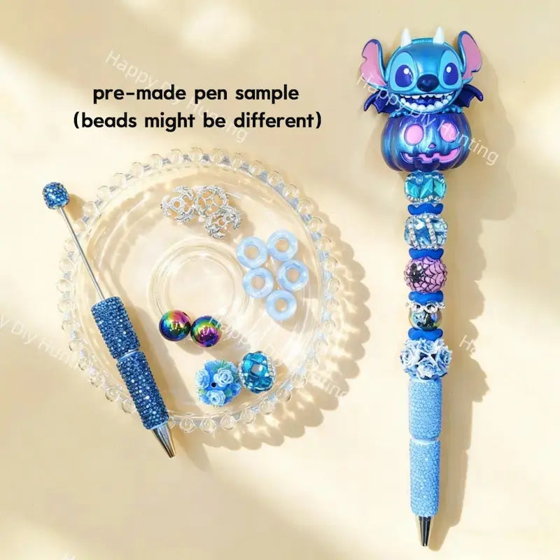 Pre-made beaded pen featuring a cute blue cartoon alien monster emerging from a metallic blue pumpkin topper, styled with blue rhinestones and sparkling beads.
