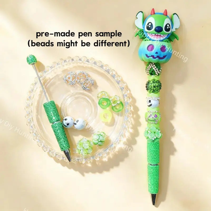 Pre-made beaded pen featuring a cute cartoon alien monster emerging from a green Halloween pumpkin topper, styled with green rhinestone beads and festive accessories.