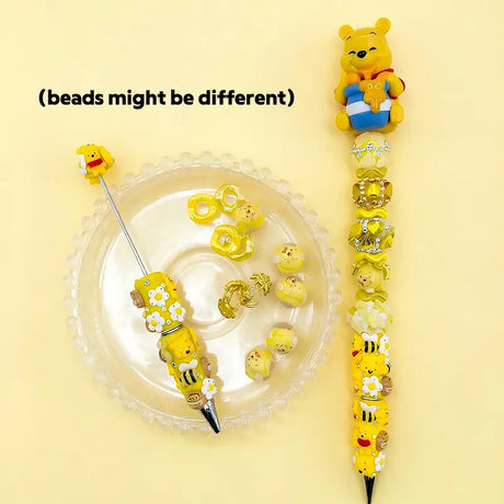 Winnie the Pooh inspired DIY beadable pen kit featuring a yellow cartoon bear pen topper, honey bee focal beads, and a crystal rhinestone barrel.